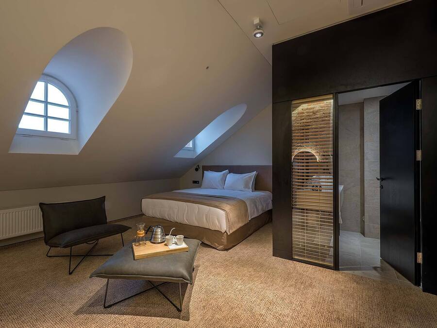Un dormitorio moderno con una cama grande, una zona de estar con una mesita de centro y un tragaluz.