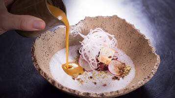 Una mano versa una salsa in una ciotola con un'insalata e diversi ingredienti.