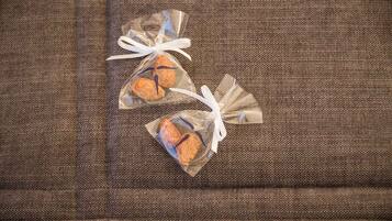 Two small, clear, plastic bags with a brown and blue design, tied with white ribbons, placed on a textured fabric surface.