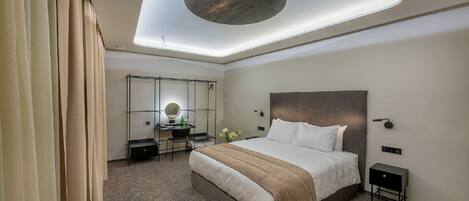 Habitación de hotel moderna con una cama grande, un escritorio con una silla, una mesita y un espejo.
