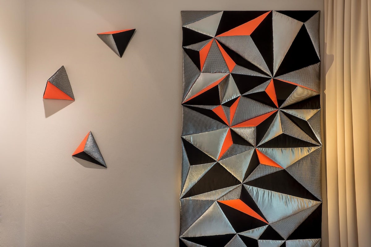 A geometric wall art with triangles and rectangles in black, gray, and orange.