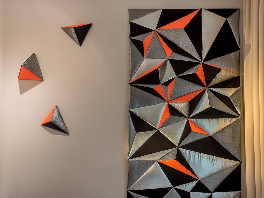 A geometric wall art with triangles and rectangles in black, gray, and orange.