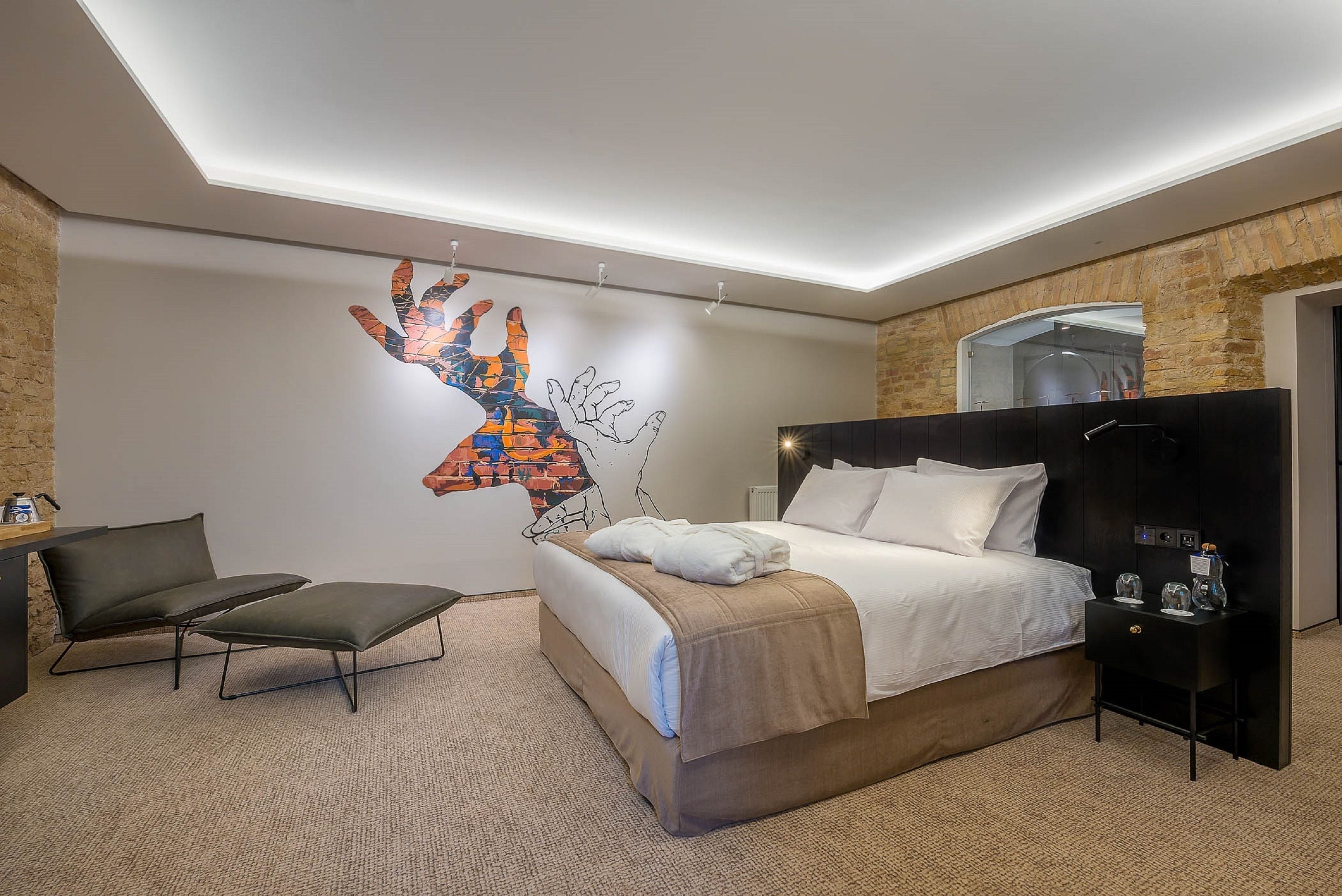 A modern hotel room with a large bed, a desk, and a chair.