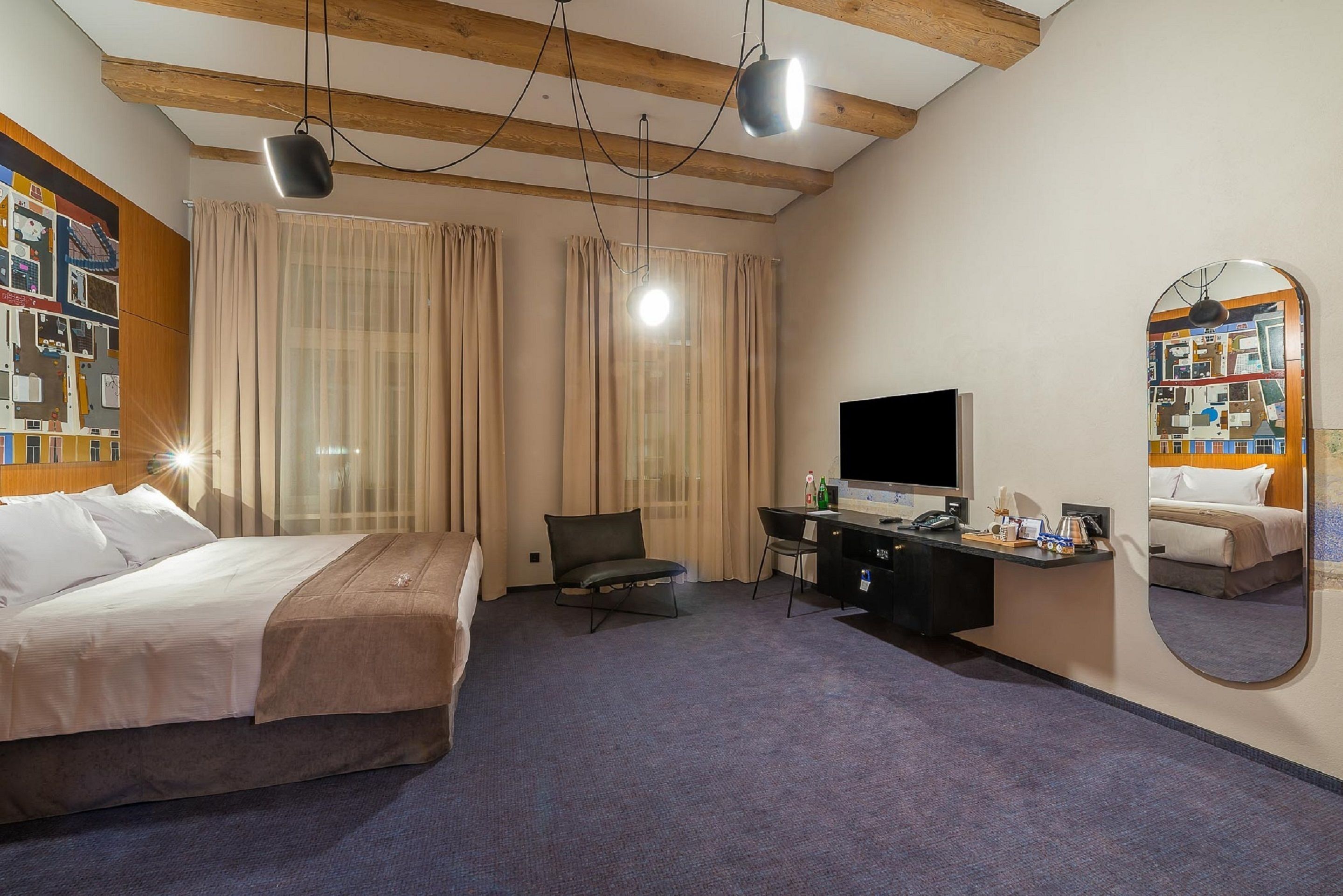 Habitación de hotel con cama, escritorio, silla, televisión y espejo.