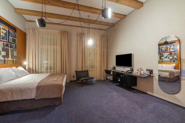 Habitación de hotel con cama, escritorio, silla, televisión y espejo.