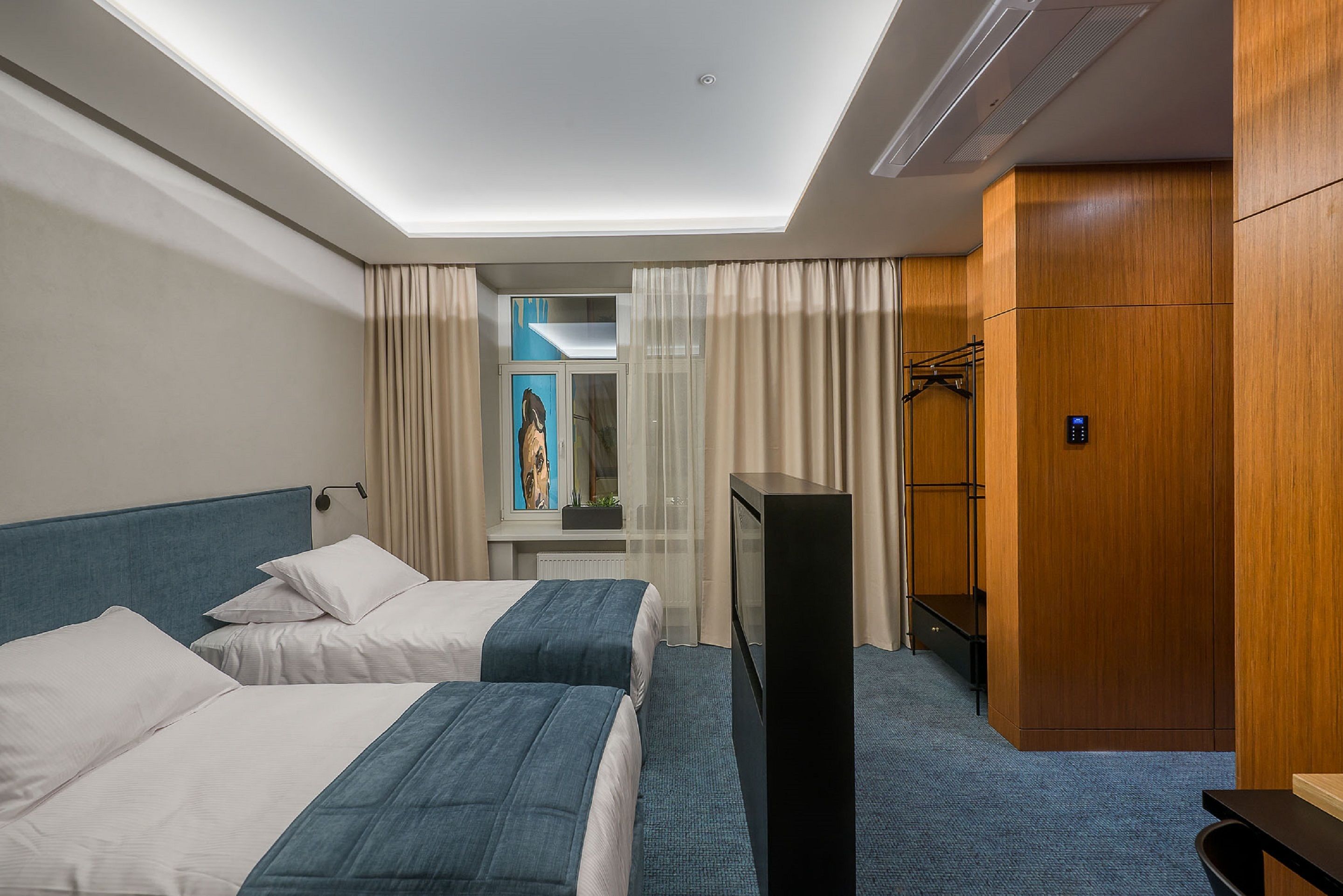 Een hotelkamer met twee bedden, een televisie, een kledingkast en een raam met gordijnen.