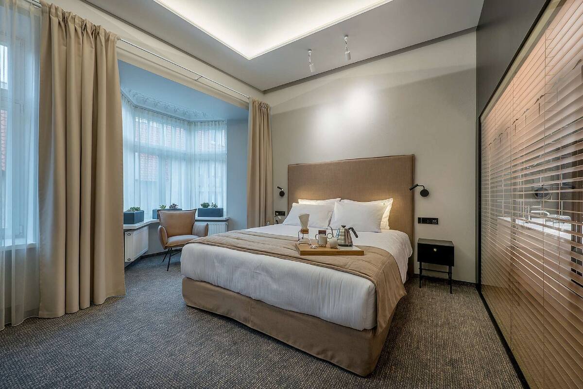 A hotel room with a large bed, a desk, and a view of the city.