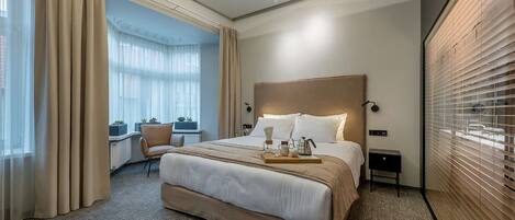 A hotel room with a large bed, a desk, and a view of the city.