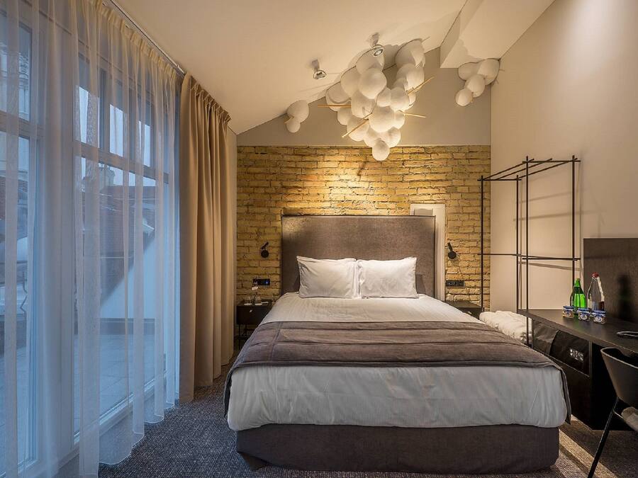 Ein modernes Hotelzimmer mit einem großen Bett, einem Schreibtisch und einer Ziegelwand.