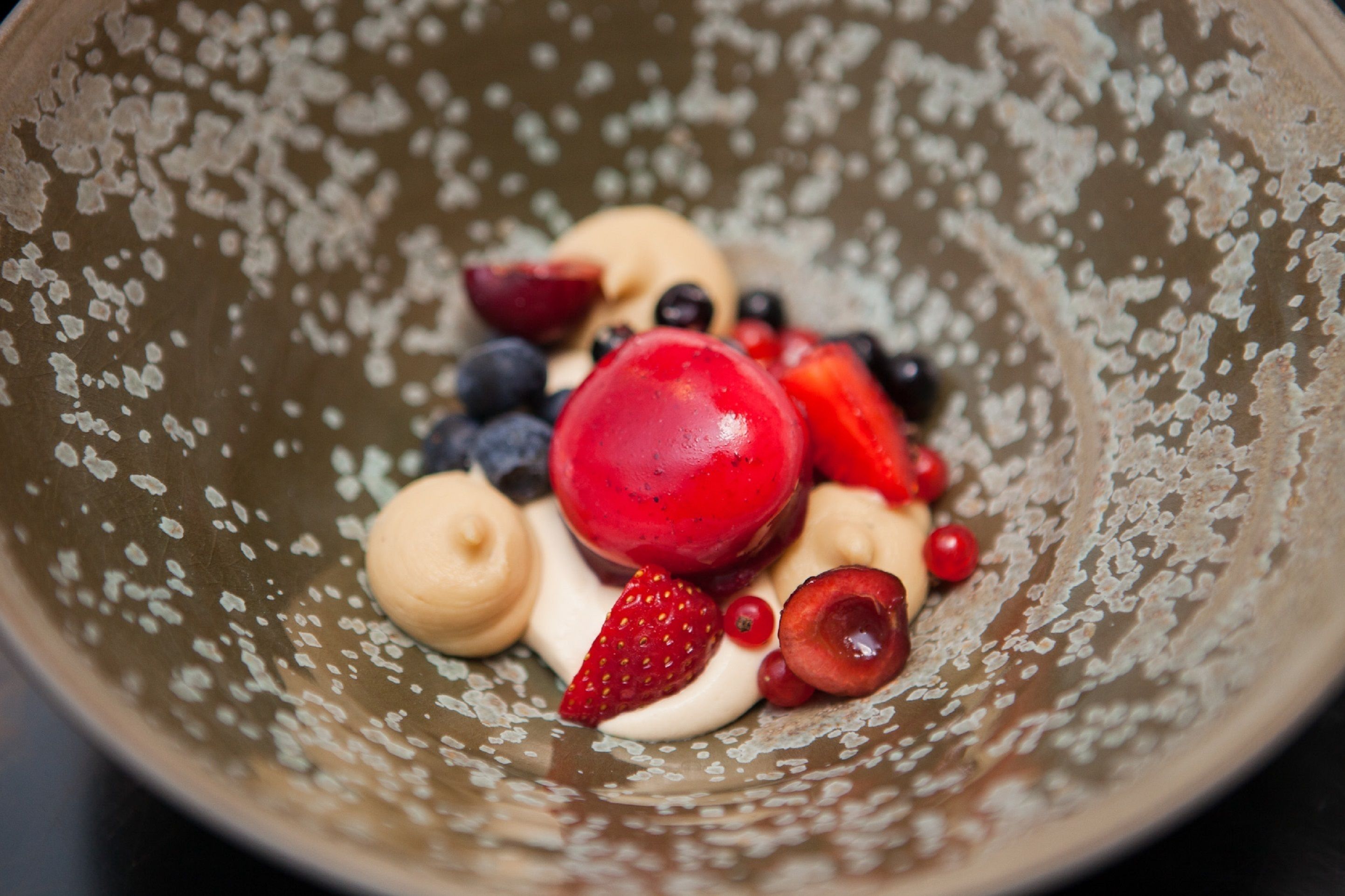 Un tazón con frutas variadas y una cucharada de crema.