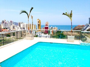 A rooftop pool with a clear view of the ocean and surrounding buildings.