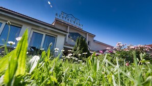 Et hotel med et skilt, der viser "HOTEL RESTAURANT", samt en velholdt have i forgrunden.
