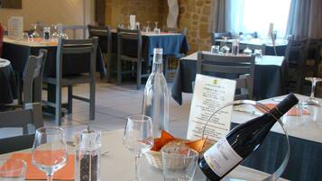 Un interior de restaurante con mesas dispuestas para comer, copas de vino y un cartel con el menú.
