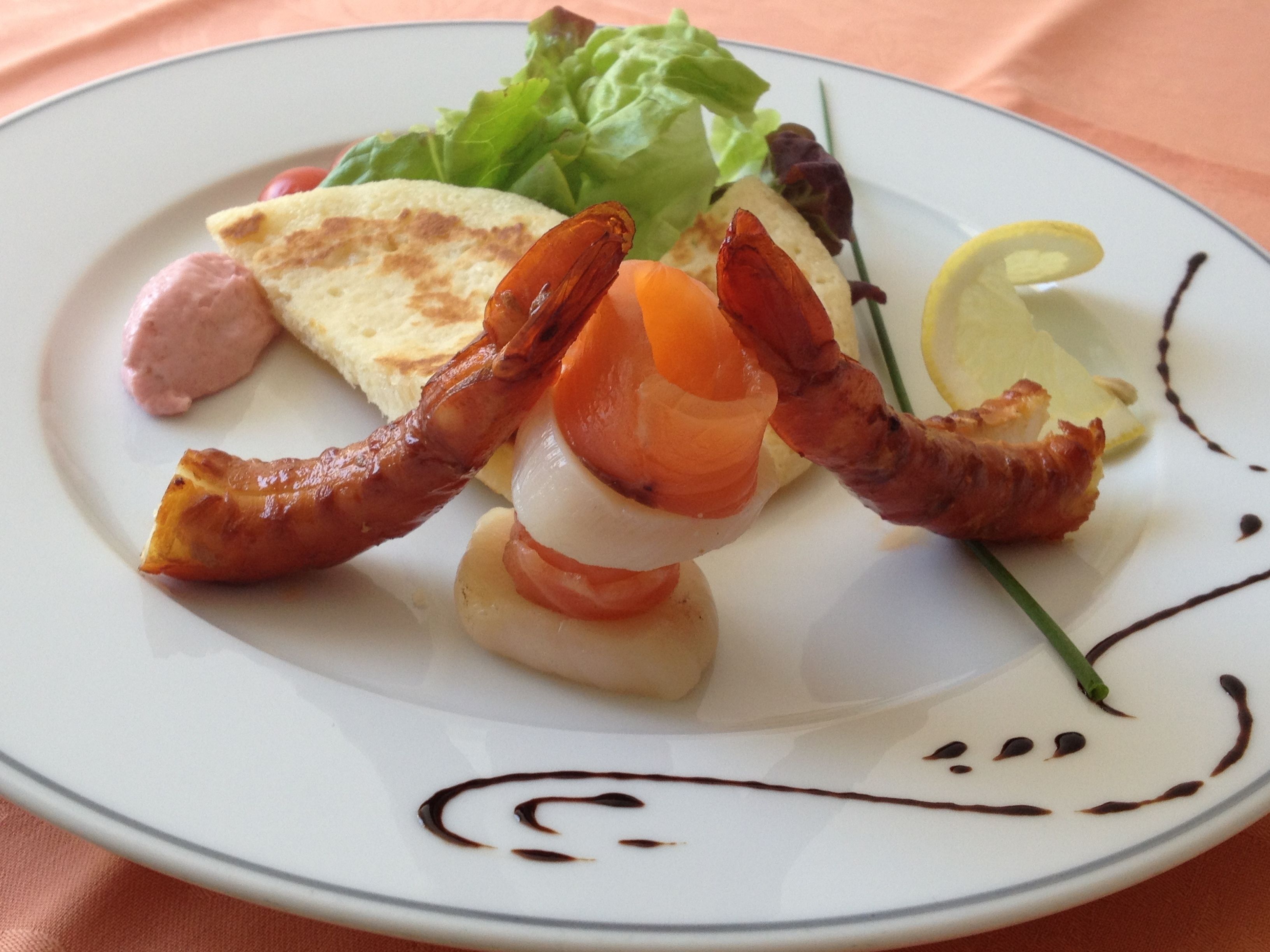 A plate with a salad, a slice of toast, and two pieces of bacon.