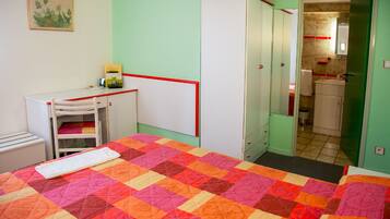 A room with a bed, a desk, a wardrobe, and a bathroom visible through an open door.
