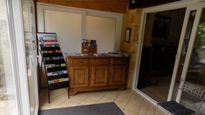 A small kitchen area with a wooden cabinet, a magazine rack, and a door leading to a balcony. - Le Jaonnet (Nabirat)
