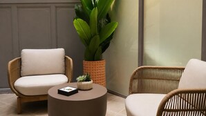 A room with two wicker chairs, a round table, and a large potted plant. - Legazpi Doce Rooms & Suites (San Sebastián)
