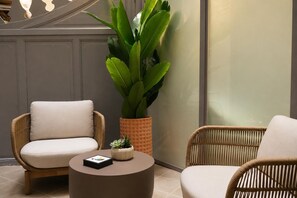 A room with two wicker chairs, a round table, and a large potted plant. - Legazpi Doce Rooms & Suites (San Sebastián)