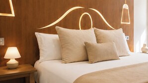 A neatly made bed with a headboard, a bedside lamp, and a wall-mounted light fixture. - Legazpi Doce Rooms & Suites (San Sebastián)