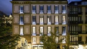 A multi-story building with balconies, a central archway, and a street below. - Legazpi Doce Rooms & Suites (San Sebastián)