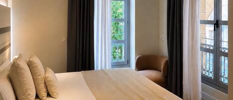 A bedroom with a bed, a chair, a window, and a door.