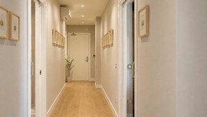 A hallway with wooden flooring, white walls, and framed pictures on the walls. - Legazpi Doce Rooms & Suites (San Sebastián)