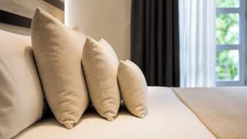 A bed with three pillows and a window with curtains.