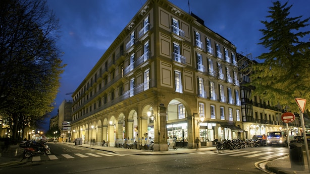 A multi-story building with a classic architectural style, featuring large windows and a central entrance with an arched doorway. - Legazpi Doce Rooms & Suites (San Sebastián)
