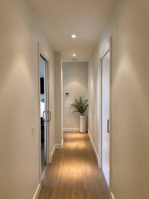 A narrow hallway with wooden flooring and white walls. - Legazpi Doce Rooms & Suites (San Sebastián)