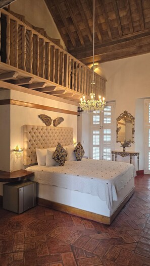 A bedroom with a large bed, a chandelier, a wooden ceiling, and a mirror. - Hotel Casa la Tablada (Cartagena)