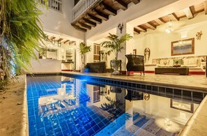 A pool area with a tiled floor, a wooden ceiling, and a seating area with a sofa and chairs. - Hotel Casa la Tablada (Cartagena)