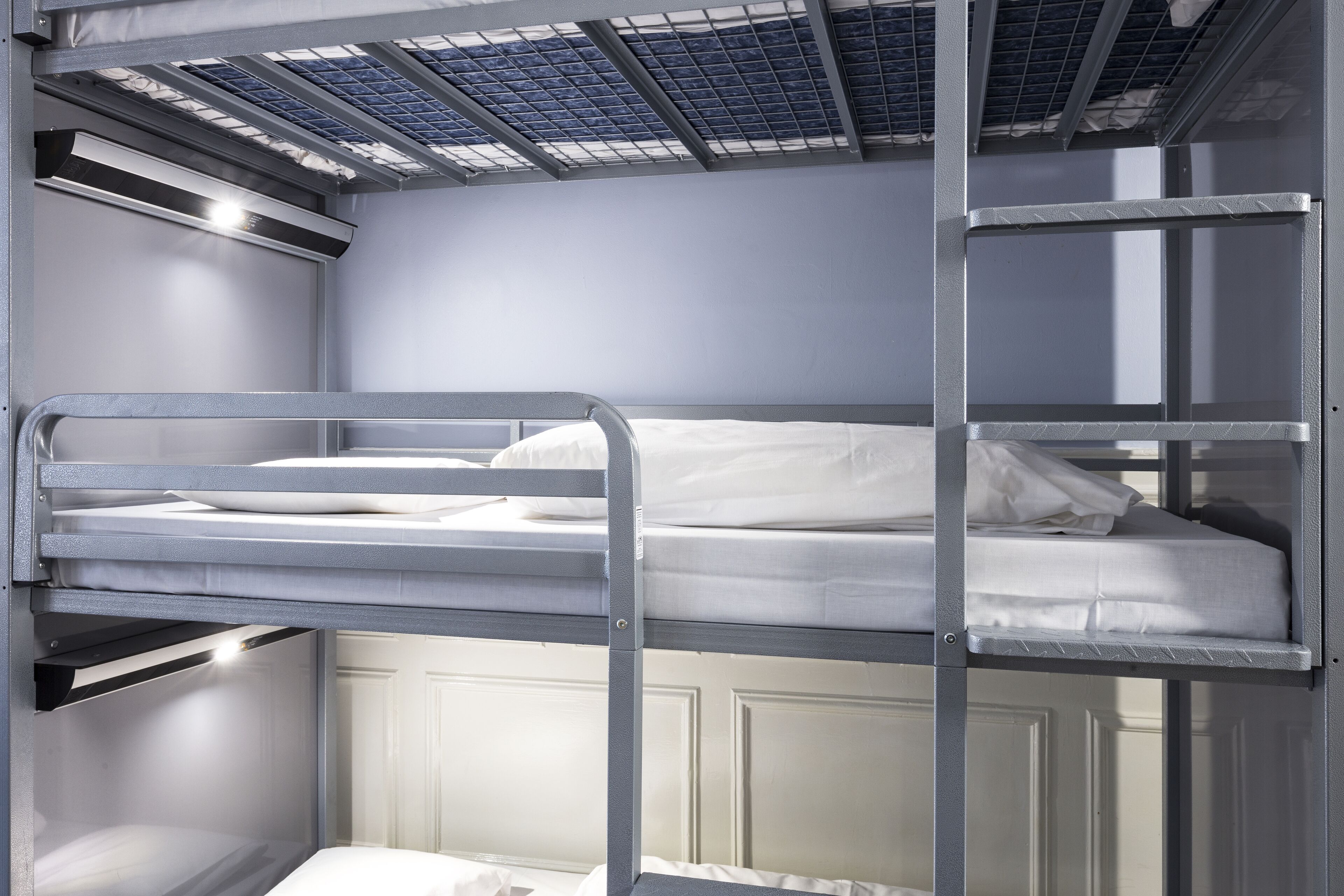A bunk bed room with metal railings, a white door, and a skylight.