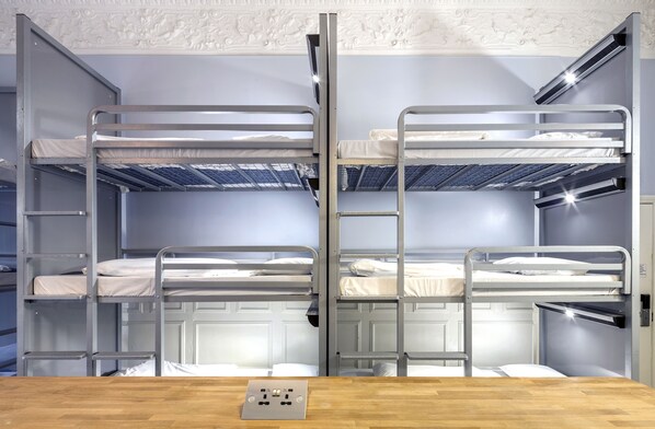 A bunk bed room with a wooden table in the foreground and a white ceiling with decorative molding. - Astor Hyde Park – 18 to 40 years (London)