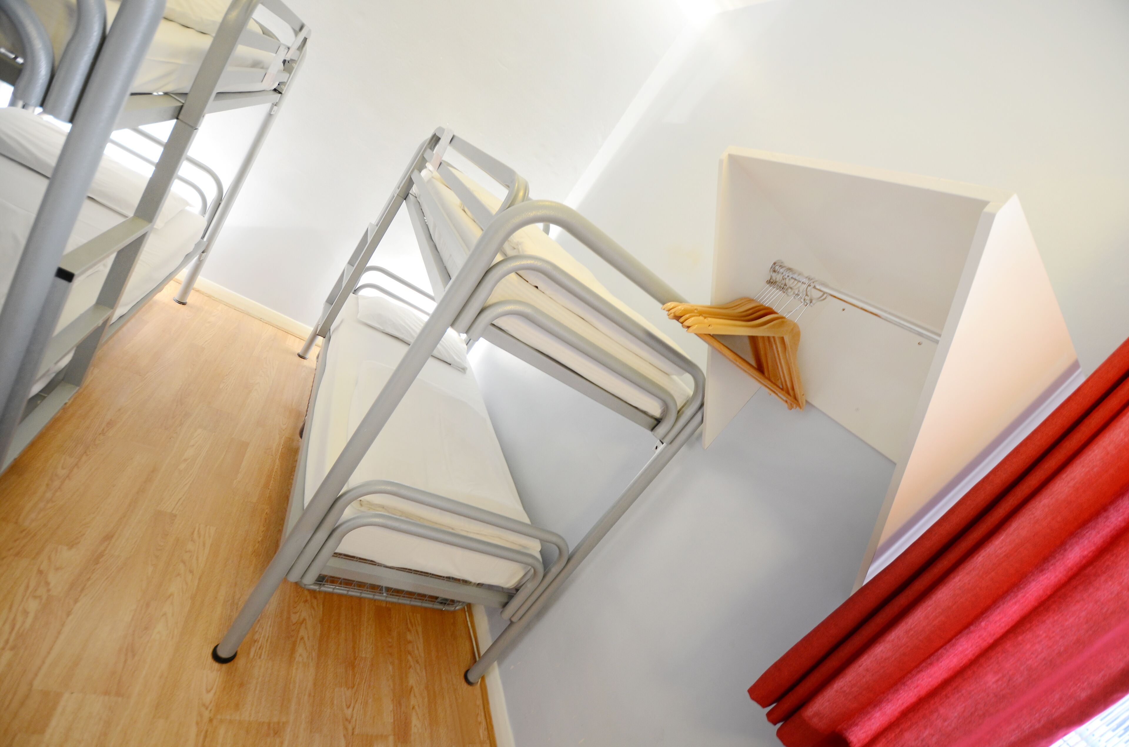 A room with a bunk bed, a small table with a chair, and a wall-mounted shelf with a mirror and some items.