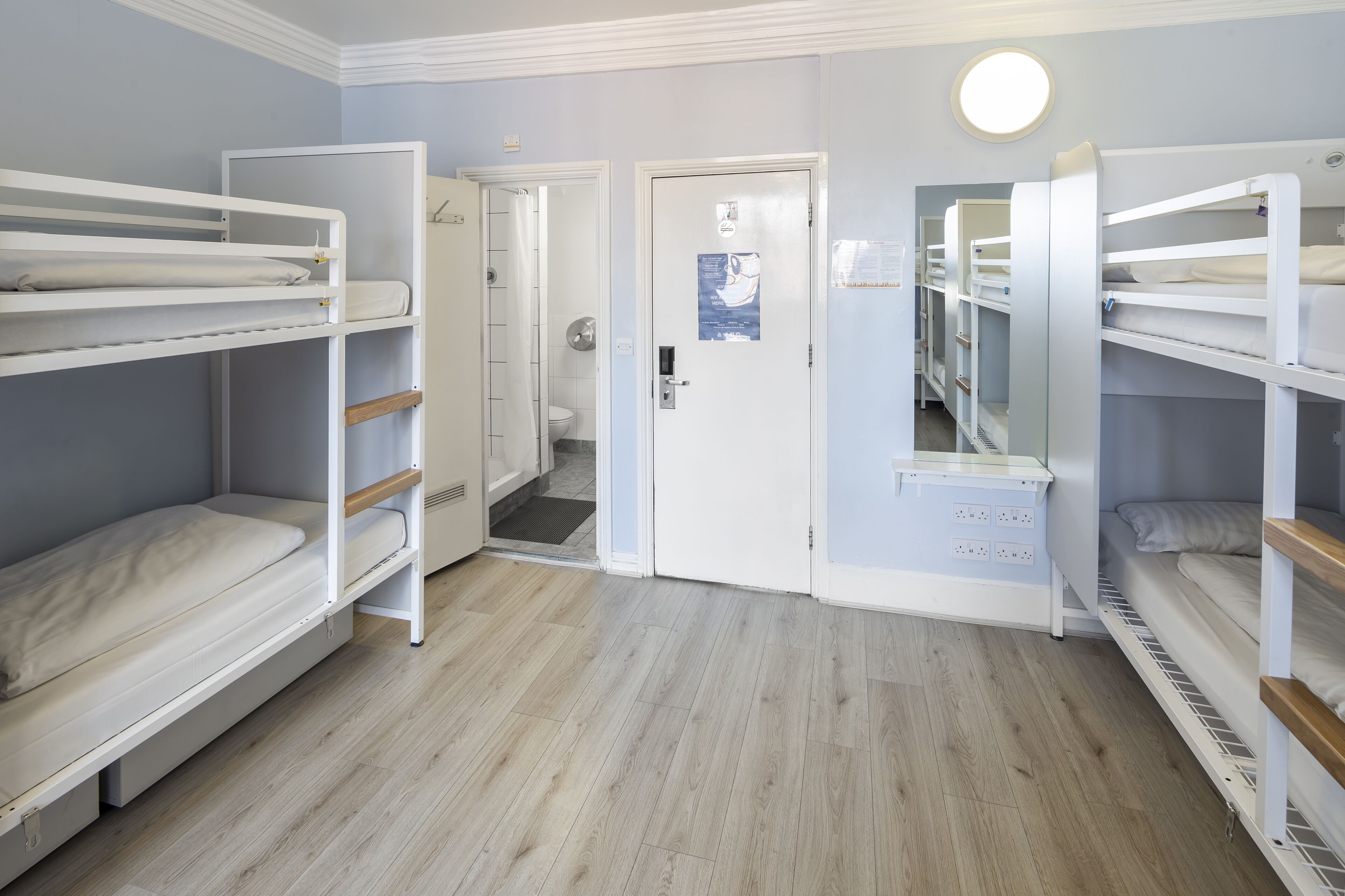 A room with bunk beds, a door, and a light fixture.
