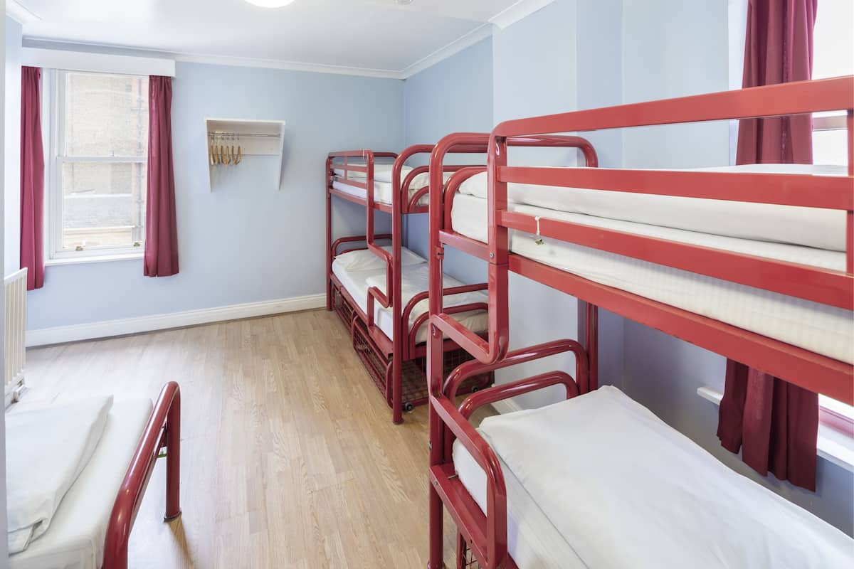 A room with bunk beds, a radiator, and a window with curtains.