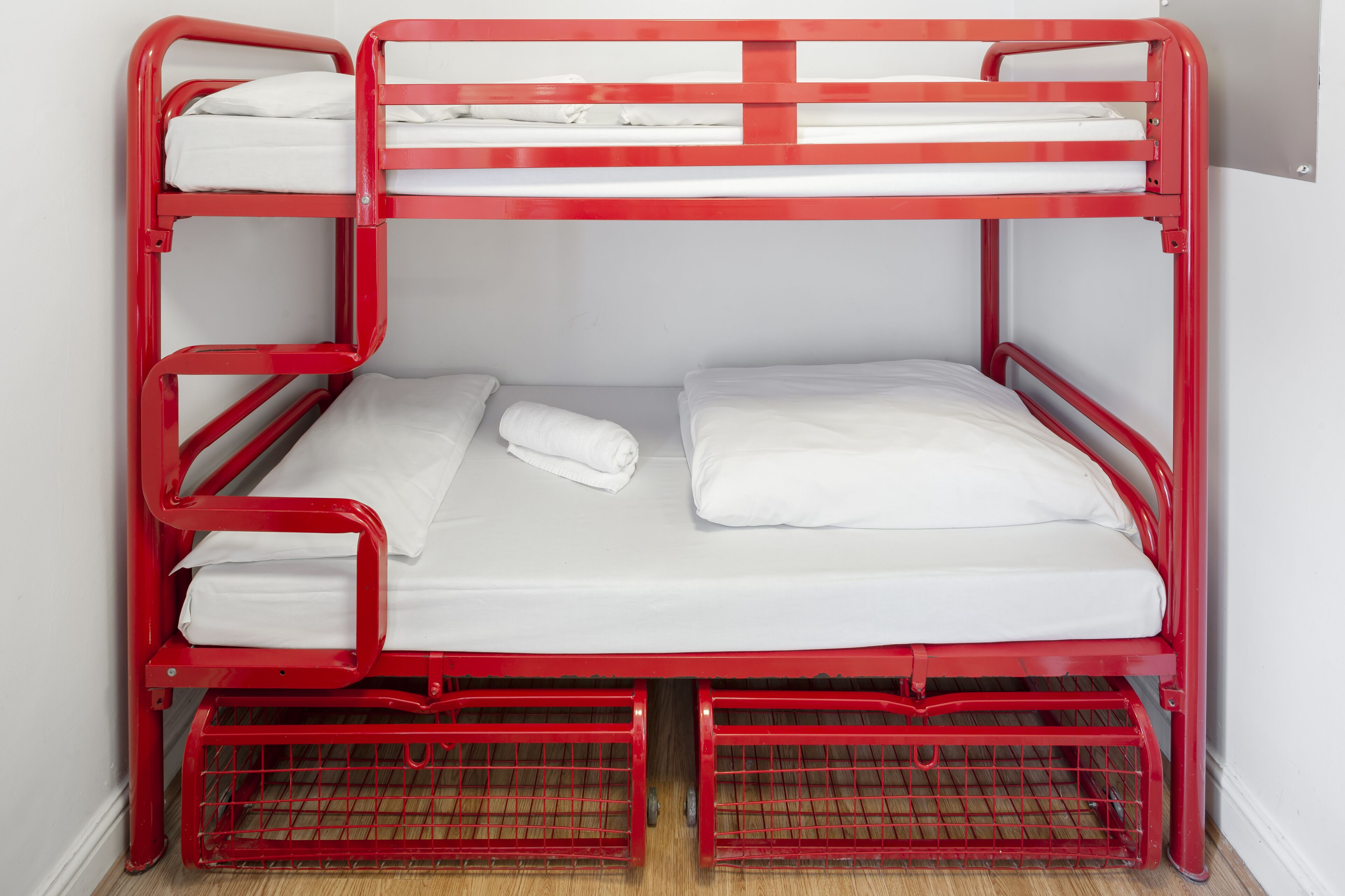 A red bunk bed with white bedding and a metal frame.