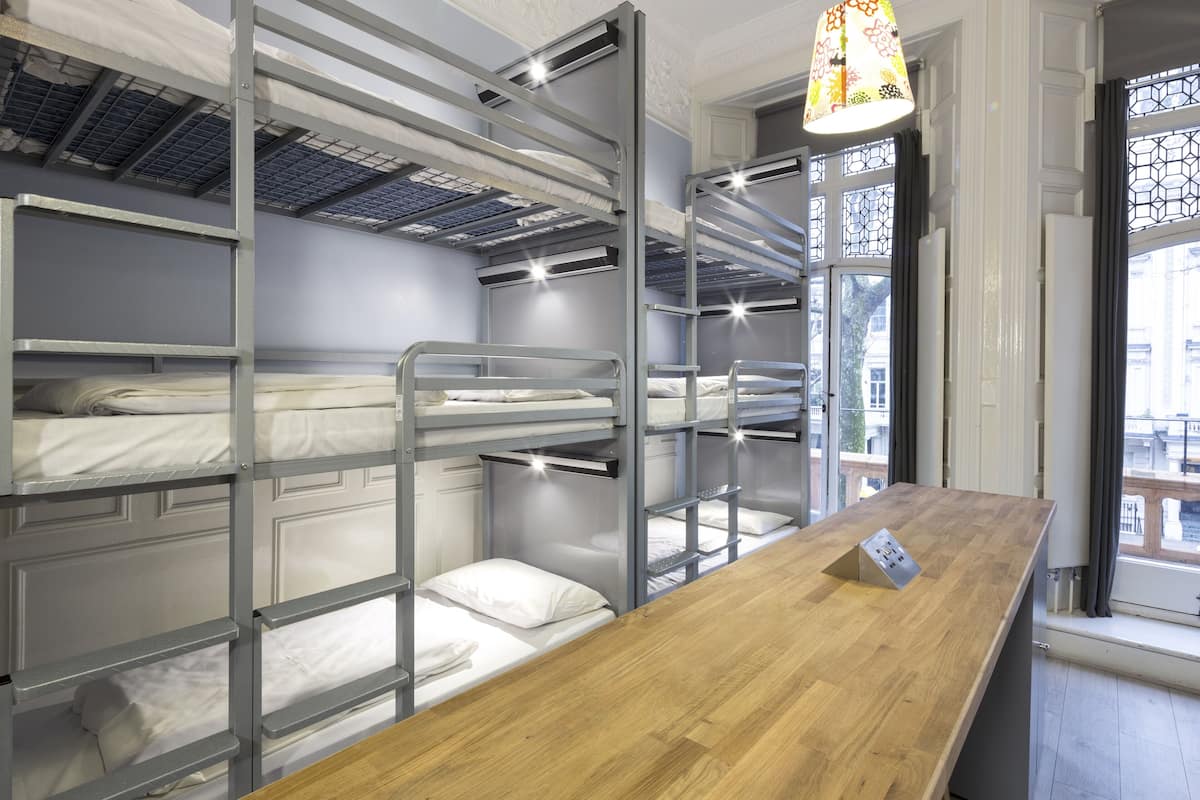 A bunk bed room with a wooden desk and a window with a view of the outside.