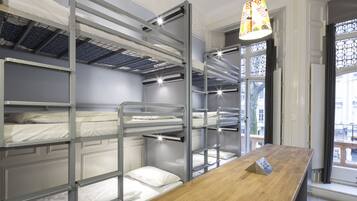 A bunk bed room with a wooden desk and a window with a view of the outside.
