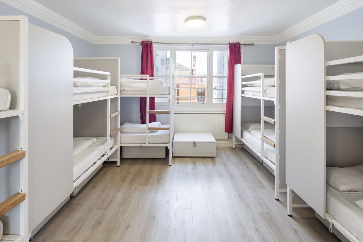 A room with bunk beds, a window with curtains, and a radiator.