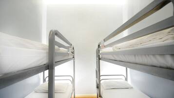 A bunk bed room with metal railings and white bedding.