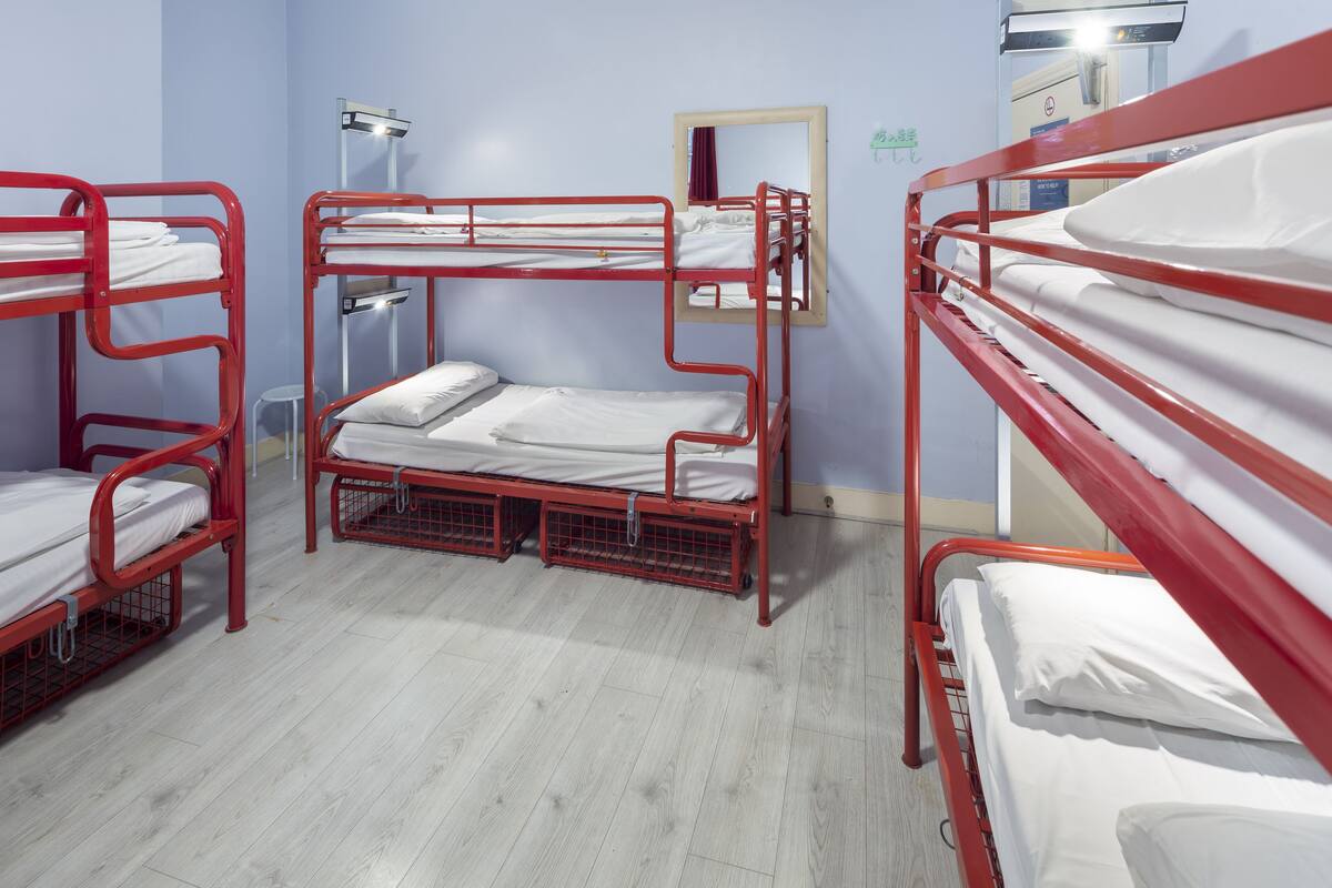 A room with bunk beds, a mirror, and a desk with a chair.