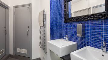 Un baño con dos lavamanos, un perchero para toallas y un espejo con un marco decorativo.