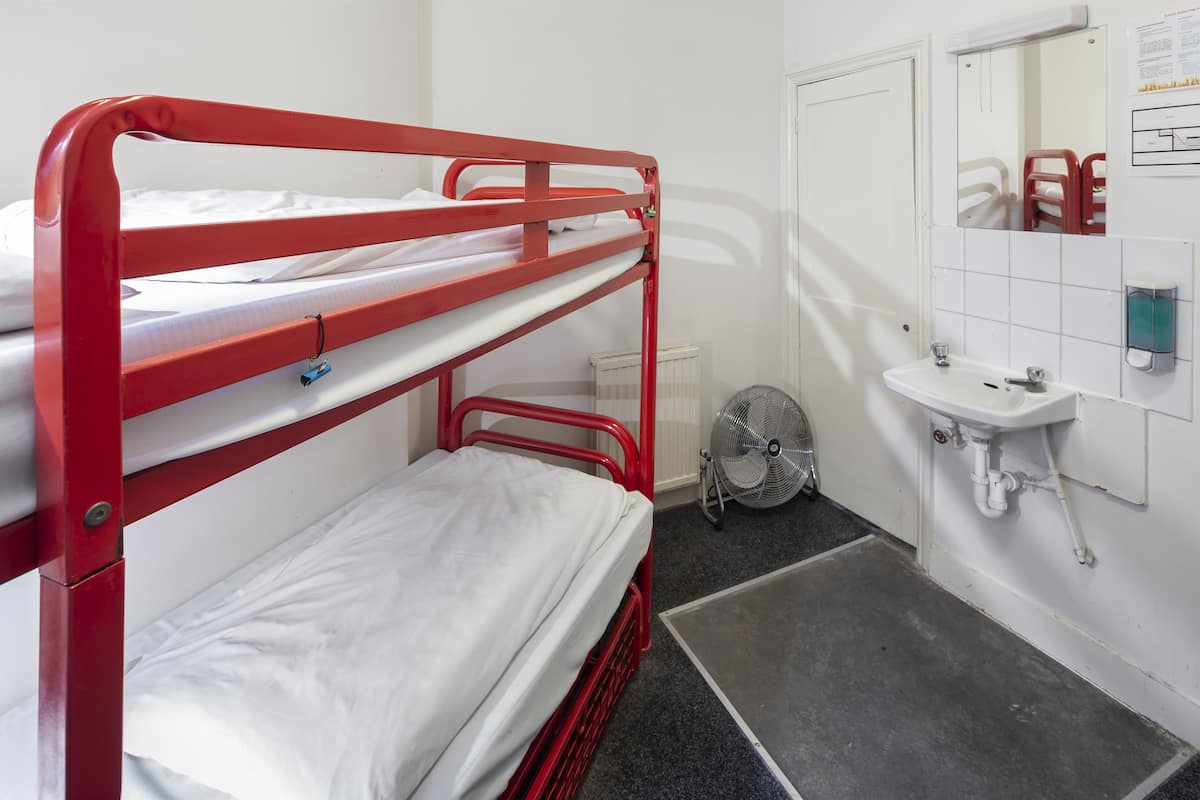A bunk bed room with a white sink and a mirror.