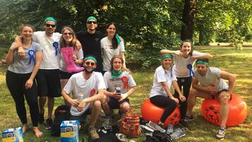 A group of people posing outdoors with a picnic setup in a park.