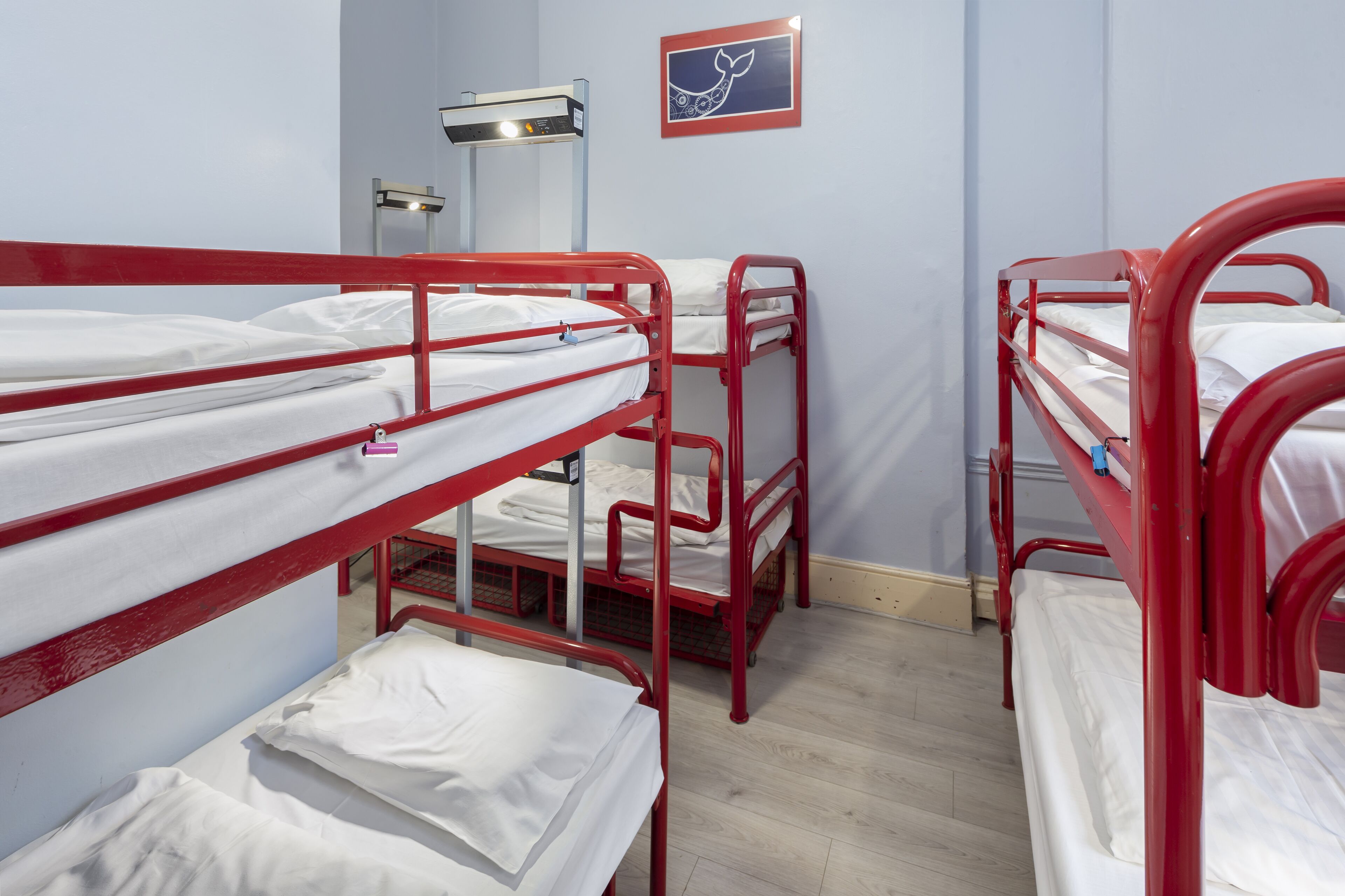 Un dormitorio con literas, un escritorio y una lámpara fijada a la pared.