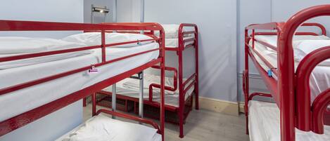 Un dormitorio con literas, un escritorio y una lámpara fijada a la pared.