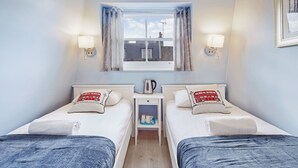 A twin room with two beds, a nightstand, a kettle, and a window with curtains. - Astor Kensington Hostel (London)