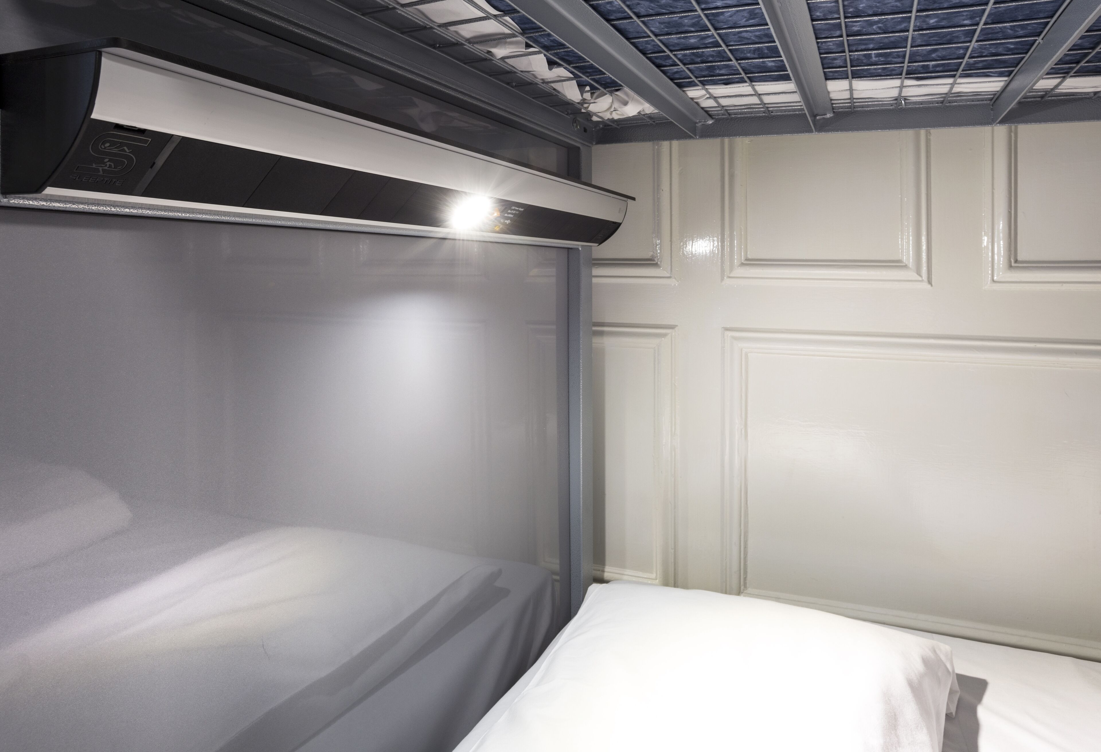 Een kamer met een bed, een plafondventilator en een lamp.