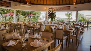 A restaurant with wooden tables and chairs, arranged in a spacious outdoor setting with large windows and red umbrellas. - Hotel Florida Sinú (Montería)